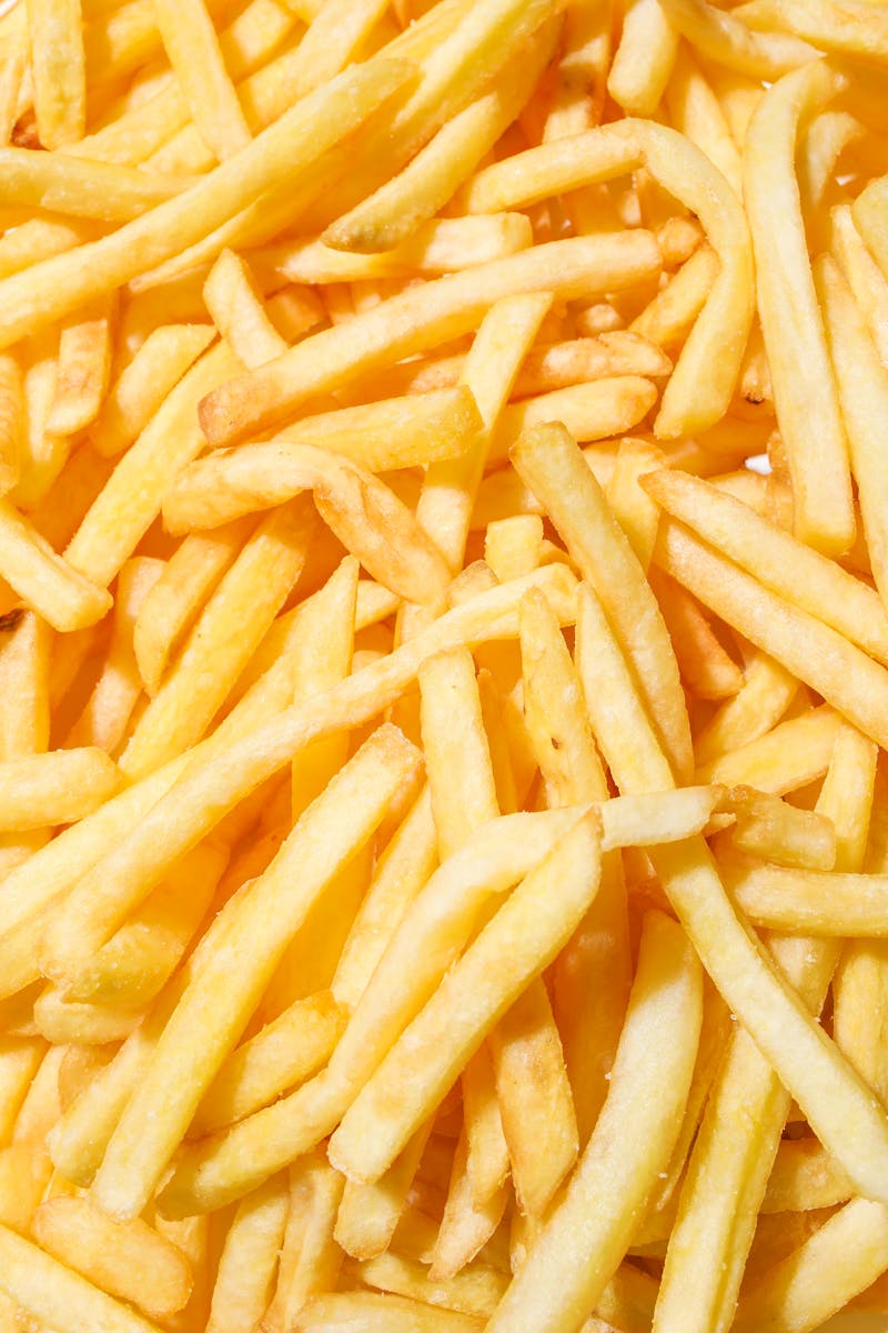 A close-up of delicious crispy French fries with a vibrant yellow background.