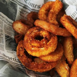 a pile of fried onion rings sitting on top of a newspaper