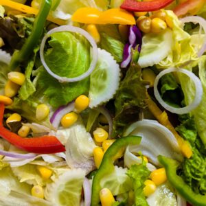 a close up of a salad with peppers and corn